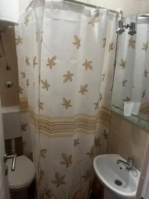 a bathroom with a shower curtain with a toilet and a sink at Apartmani Sunce in Bar
