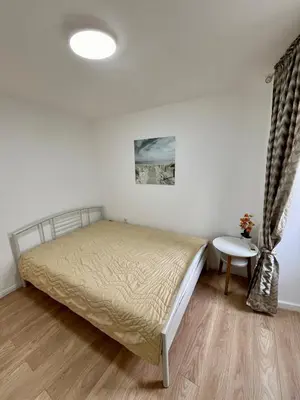 a white bedroom with a bed and a table at Milena in Petrovac na Moru