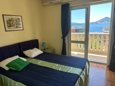 a bedroom with a bed with a view of the ocean at Apartments Villa Pržno in Sveti Stefan