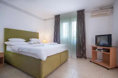 a bedroom with a large bed and a television at Apartments Grand in Sveti Stefan