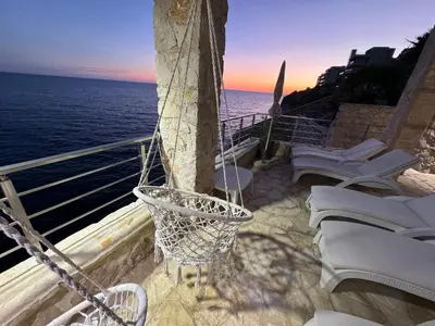 a balcony with chairs and a basketball hoop on the ocean at Apart Lux Beciragic in Dobra Voda
