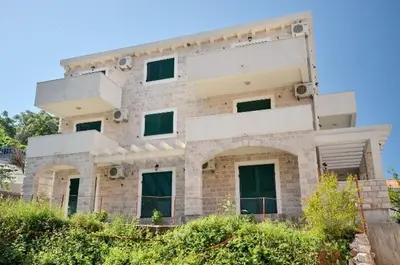 a building on top of a hill with bushes at Guest House Villa Pastrovka in Sveti Stefan