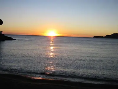 a sunset on the beach with the sun setting at Guest House Villa Pastrovka in Sveti Stefan