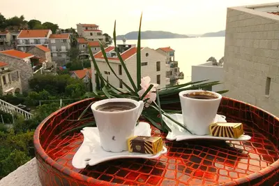 two cups of coffee on a table on a balcony at Guest House Villa Pastrovka in Sveti Stefan