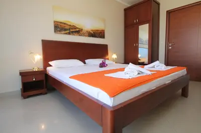 a bedroom with a large bed with an orange blanket at Guest House Villa Pastrovka in Sveti Stefan