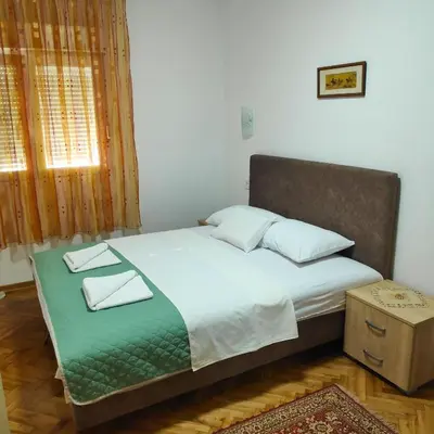 a bed with two pillows on it in a bedroom at Apartmani Asanović in Budva