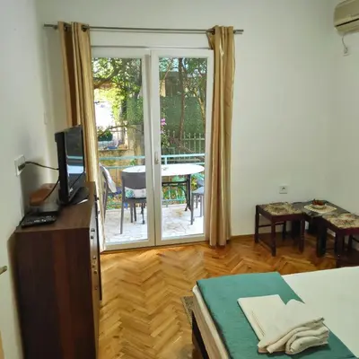 a living room with a sliding glass door with a table at Apartmani Asanović in Budva