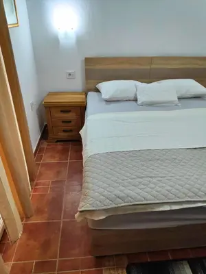 a bedroom with a bed and a wooden nightstand at Apartmani Asanović in Budva
