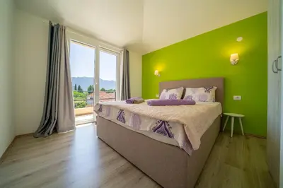 a bedroom with a bed with green walls and a window at Apartments Kingfisher in Virpazar