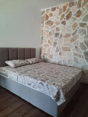 a bed in a room with a stone wall at Apartments Kingfisher in Virpazar