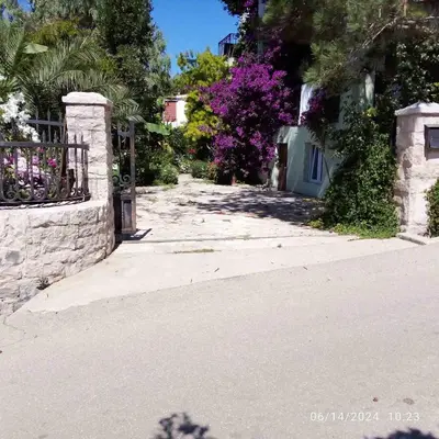 an empty street with a fence and purple flowers at Vila Maljevik in Sutomore
