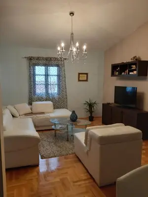 a living room with white furniture and a chandelier at Vila Maljevik in Sutomore