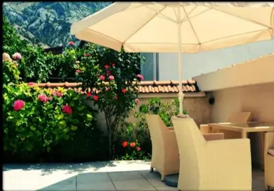 a patio with an umbrella and chairs and flowers at Kotor Sunrise Apartments in Kotor