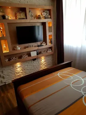 a bedroom with a tv on a brick wall at Apartmani vuk in Cetinje