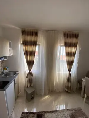 a kitchen with white curtains and a window at Apartments Gusar in Ulcinj