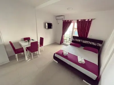 a bedroom with a large bed and a table and chairs at Apartmani Agi in Budva