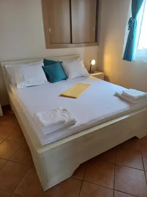 a large bed with white sheets and blue pillows at Guest House Luna in Virpazar