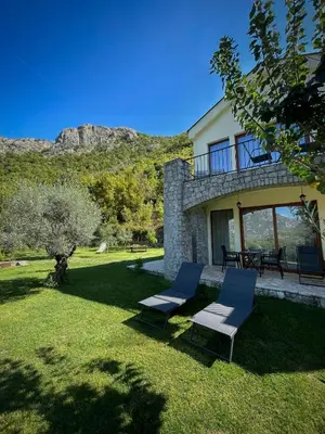 a house with two chairs and a table in the yard at Prevalis Nature Cottage in Virpazar