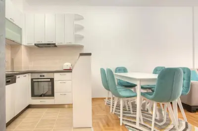 a kitchen with a white table and blue chairs at Apartman 104 in Budva