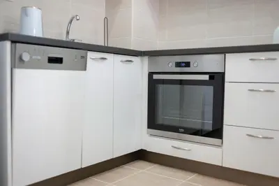 a white kitchen with a sink and a oven at Apartman 104 in Budva