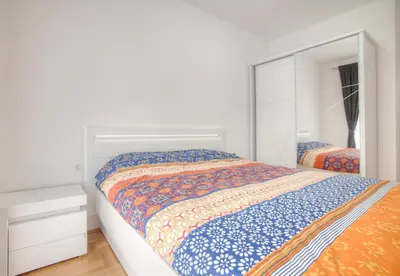 a white bedroom with a bed and a mirror at Apartman 104 in Budva