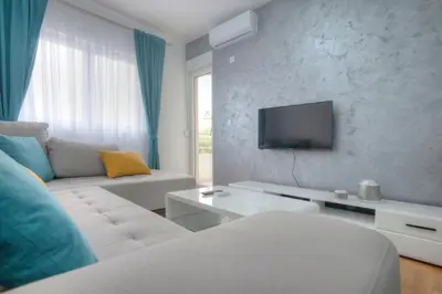 a living room with a white couch and a tv at Apartman 104 in Budva