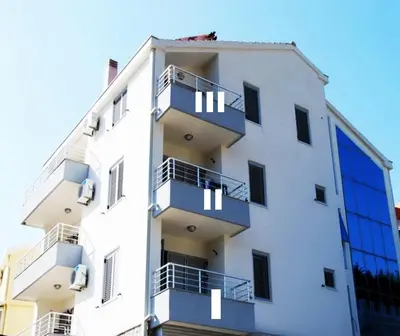 a white building with balconies on the side of it at Apartments Ivanović in Budva