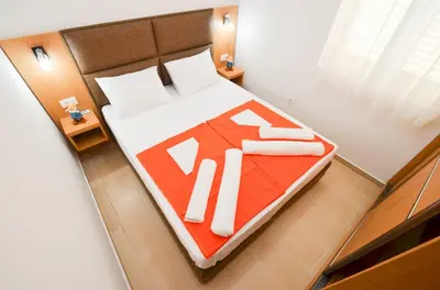 a bedroom with a large bed with a red blanket at Apartments Ivanović in Budva