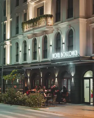 a group of people sitting at tables outside of a building at Boscovich Boutique Hotel in Podgorica
