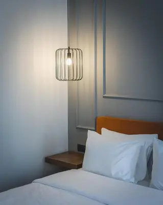 a bedroom with a bed with a lamp and pillows at Boscovich Boutique Hotel in Podgorica