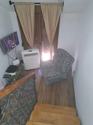 a living room with a chair and a television at APARTMANI MIA VUKSANOVIC in Cetinje