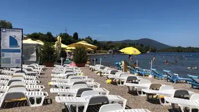 a row of white chairs on a beach next to the water at Vila Jovanka in Tivat