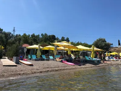 a group of people sitting on a beach with umbrellas at Vila Jovanka in Tivat