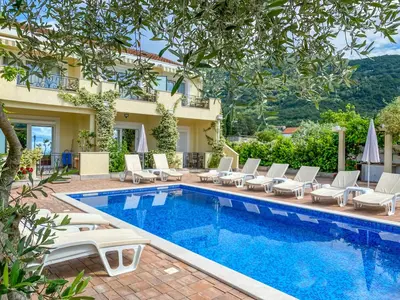 a villa with a swimming pool and chairs and a building at Luxurious Apartments Aria in Budva