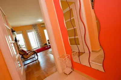 a room with orange walls and a hallway with a mirror at Tea Lux Apartment in Kotor