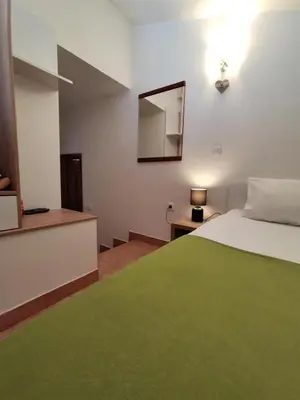 a bedroom with a green bed and a mirror at Guest House Jedro in Petrovac na Moru