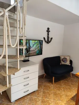 a living room with a tv and a chair at Guest House Jedro in Petrovac na Moru