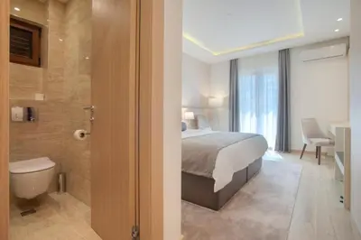 a bedroom with a bed and a bathroom with a toilet at Hotel Vela in Budva
