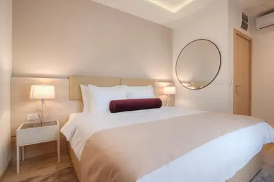 a bedroom with a large white bed and a mirror at Hotel Vela in Budva