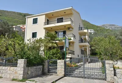a building with a fence in front of it at Apartments and Rooms Iva in Petrovac na Moru