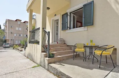 a patio with a table and chairs outside of a house at Apartments and Rooms Iva in Petrovac na Moru