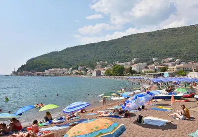 a group of people on a beach with umbrellas at Apartments and Rooms Iva in Petrovac na Moru