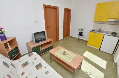 a living room with a table and a kitchen at Apartments and Rooms Iva in Petrovac na Moru