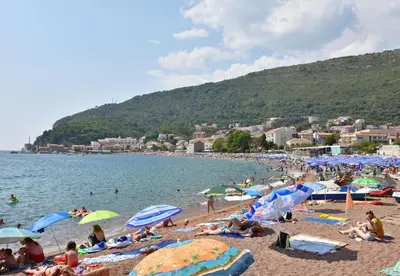 a group of people on a beach with umbrellas at Apartments and Rooms Iva in Petrovac na Moru