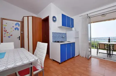 a kitchen with blue cabinets and a table and a balcony at Apartments Siljak in Petrovac na Moru