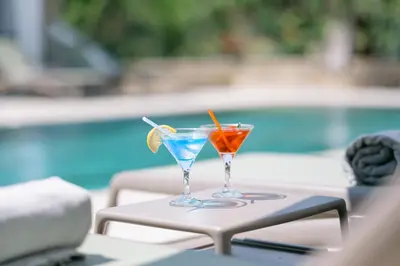 two cocktails sitting on a table next to a pool at B&B Lovac in Ulcinj