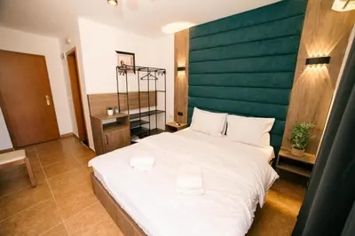 a bedroom with a large white bed with a green headboard at Hotel Dajti in Ulcinj