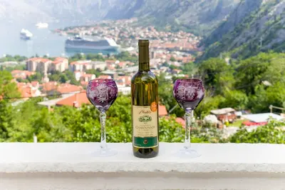 a bottle of wine and two wine glasses on a ledge at Apartment Kalle in Kotor