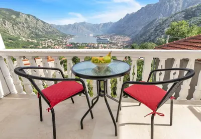 a table with two chairs and a bowl of fruit on a balcony at Apartment Kalle in Kotor