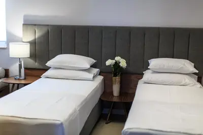 two beds in a hotel room with a vase of flowers at Regina del Mare in Bar